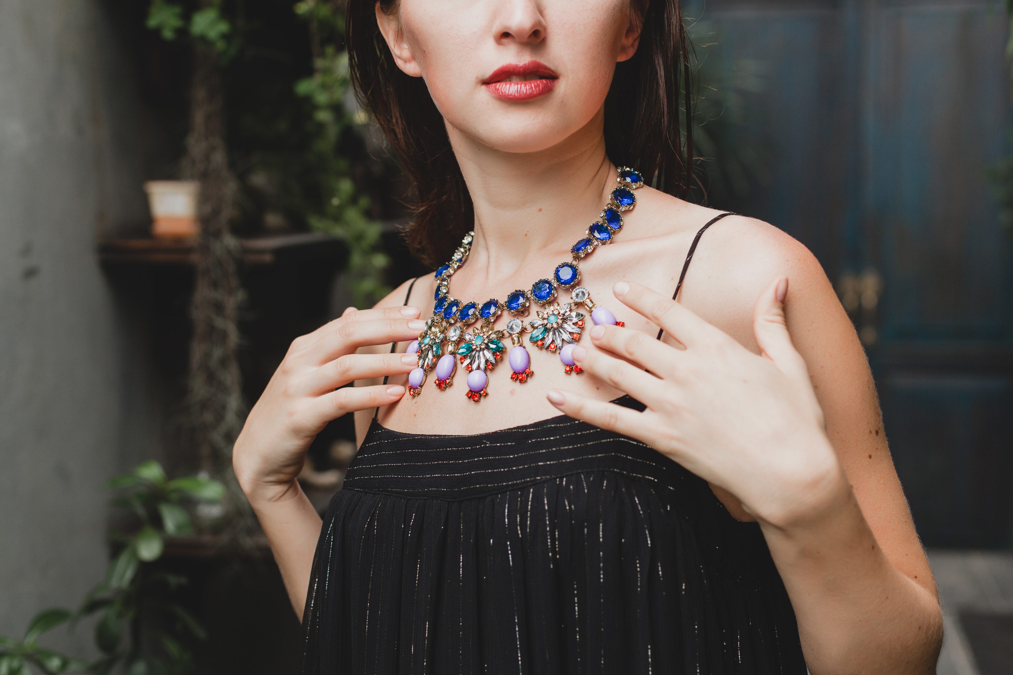 close up details of jewelry of young attractive woman in stylish black dress posing at tropical villa, sexy, elegant summer style, fashionable necklace accessories