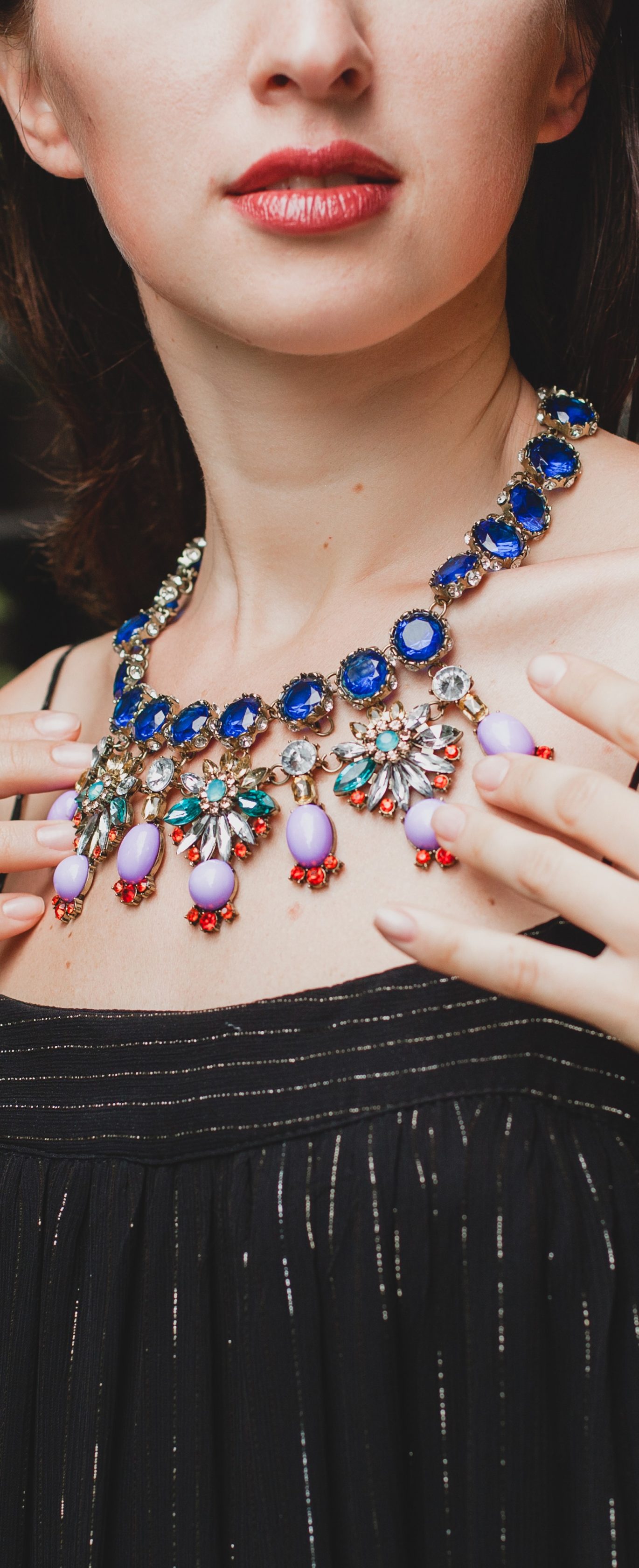 close up details of jewelry of young attractive woman in stylish black dress posing at tropical villa, sexy, elegant summer style, fashionable necklace accessories