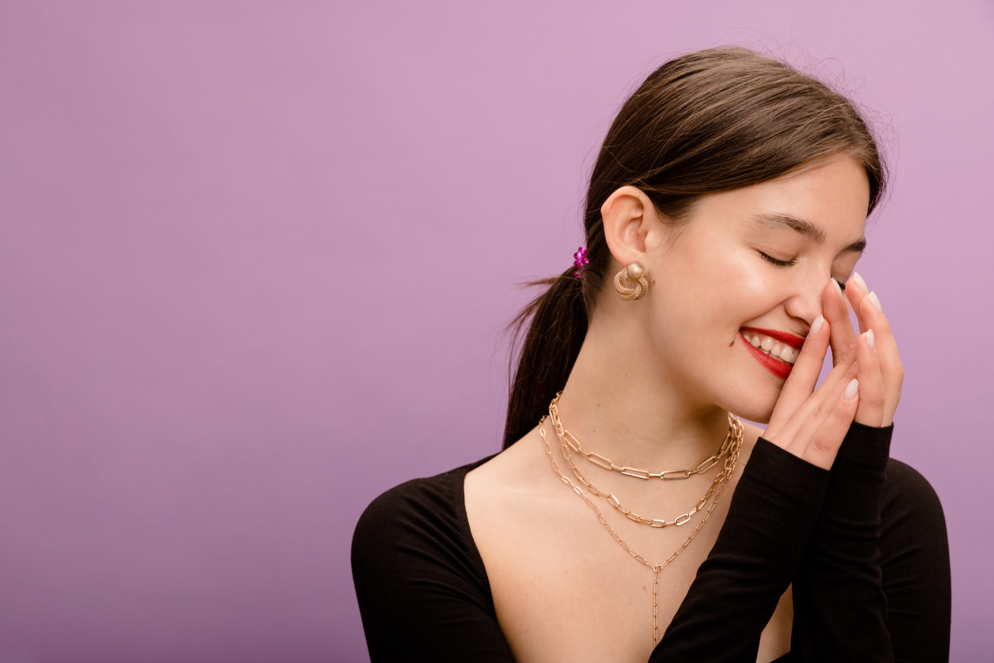 closeup-cute-young-caucasian-brunette-woman-smiles-with-her-teeth-closing-eyes-purple-background-lifestyle-different-emotions-leisure-concept